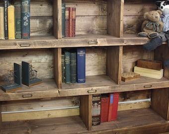 May include: A wooden bookshelf with multiple shelves and cubbyholes. The shelves are filled with books, bookends, and decorative items. There are two stuffed animals on the top shelf.