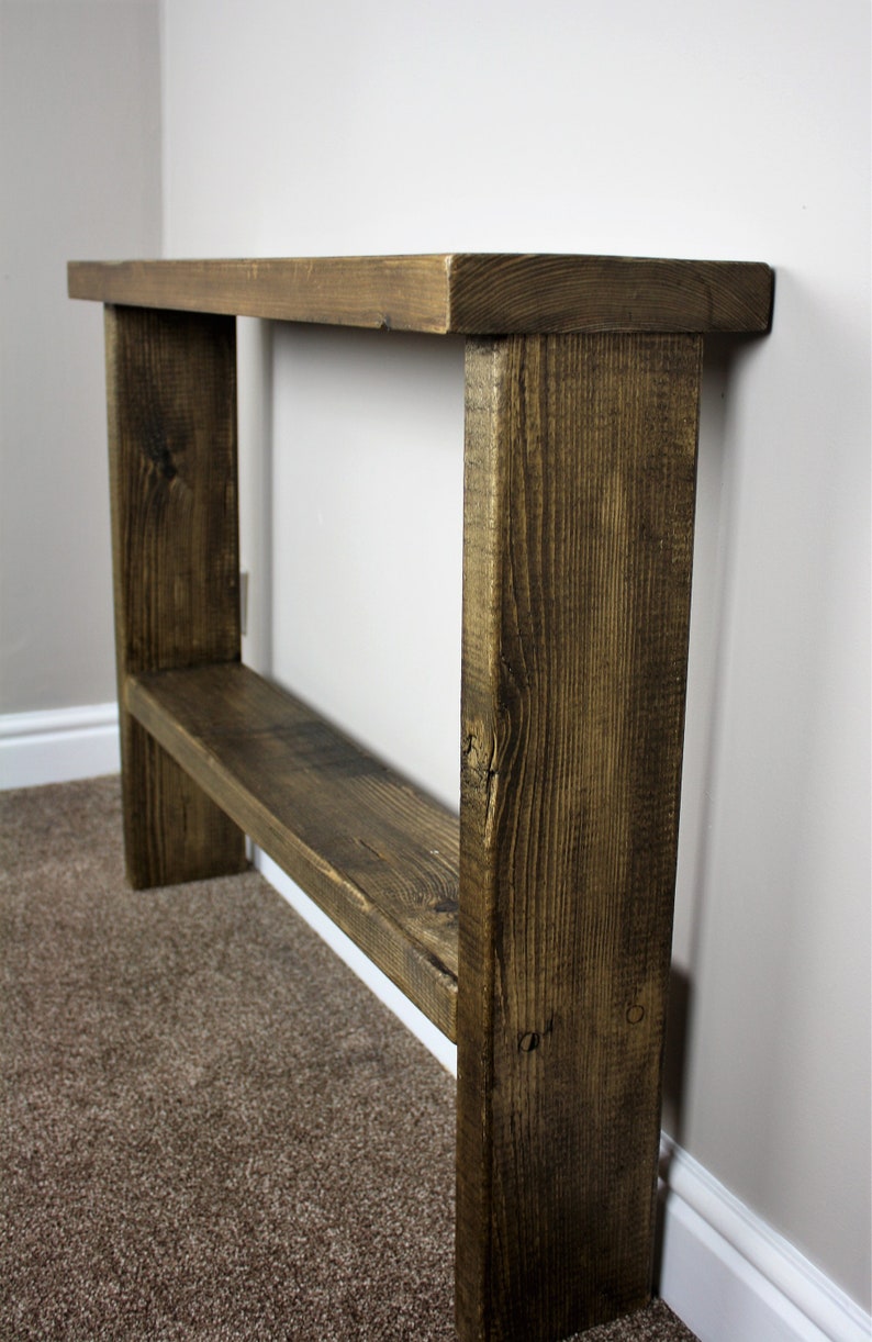 May include: A rustic wooden console table with a dark brown stain. The table has a single shelf and is made of reclaimed wood.