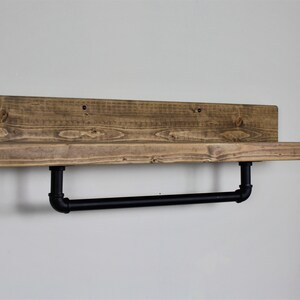 Pu&ograve; includere: Un ripiano in legno rustico con una barra porta asciugamani in metallo nero. Il ripiano &egrave; realizzato in legno riciclato e ha una finitura naturale. La barra porta asciugamani &egrave; fissata al ripiano con due tubi in metallo nero.