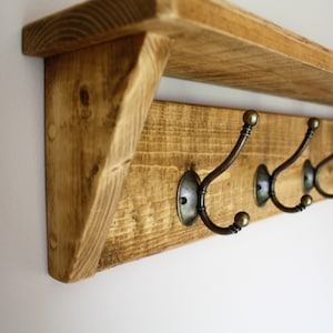 Peut inclure: &Eacute;tag&egrave;re en bois rustique avec un porte-manteau comprenant six crochets en laiton antique. L'&eacute;tag&egrave;re est en bois de r&eacute;cup&eacute;ration et a une finition naturelle.