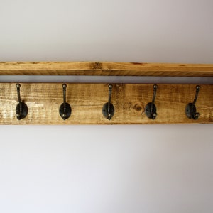 Peut inclure: Une &eacute;tag&egrave;re en bois rustique avec cinq crochets en m&eacute;tal. L'&eacute;tag&egrave;re est en bois de r&eacute;cup&eacute;ration et a une finition naturelle. Les crochets sont de couleur bronze fonc&eacute; et sont fix&eacute;s au bas de l'&eacute;tag&egrave;re.