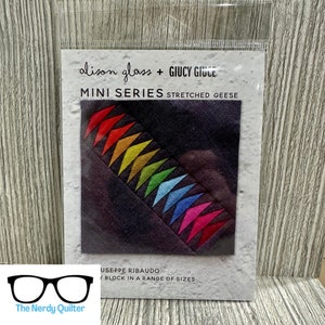 May include: A package featuring a fabric panel with a colorful geometric design. The panel has a dark background with a diagonal row of colorful triangles in shades of red, orange, yellow, green, blue, and pink. Text reads "alison glass + GIUCY GIUCE MINI SERIES STRETCHED GEESE".