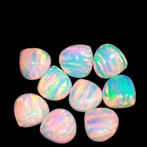 May include: Nine polished opal gemstones with a pear-like shape. The opals display a range of colors, including pink, blue, green, and yellow, with a shimmering, iridescent effect. The gemstones are set against a black background.