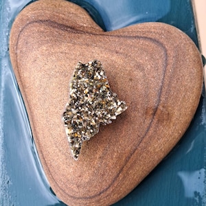 May include: A heart-shaped stone with a gold glitter outline of the state of Maine.