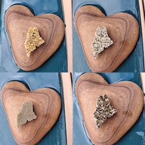 May include: Four wooden heart-shaped ornaments with a gold glitter outline. Each heart features a cutout of the state of Maine, filled with different colored glitter.