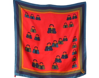 May include: A red silk scarf with a blue and green border. The scarf features a repeating pattern of navy blue handbags with gold accents.