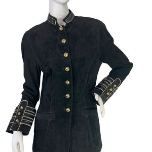 May include: A black suede jacket with gold buttons and a black and white trim on the collar and cuffs.