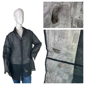 May include: A black sheer button-up shirt with a subtle pattern of feathers. The shirt is loose-fitting and has a relaxed silhouette.