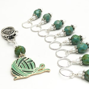 May include: Set of 7 turquoise and silver stitch markers with a yarn ball charm. Each marker features a turquoise bead with silver accents and a silver ring.