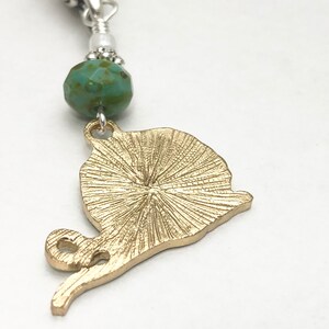 May include: Gold-toned snail charm with a textured shell and a turquoise bead.
