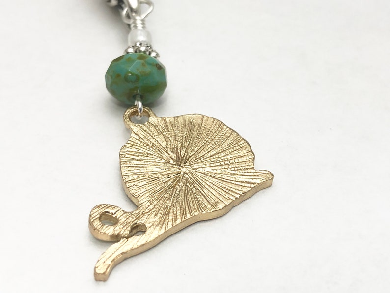 May include: Gold-toned snail charm with a textured shell and a turquoise bead.