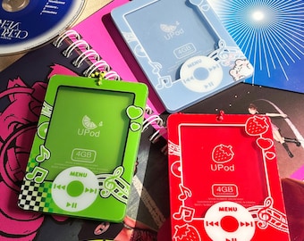 May include: Three rectangular plastic photo card holders designed to resemble vintage digital music players. One is light blue, one is lime green, and one is red. Each features a printed circular menu button, 4GB text, and musical notes.