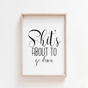 May include: A framed print with a white background and black text that reads "Shit's about to go down."