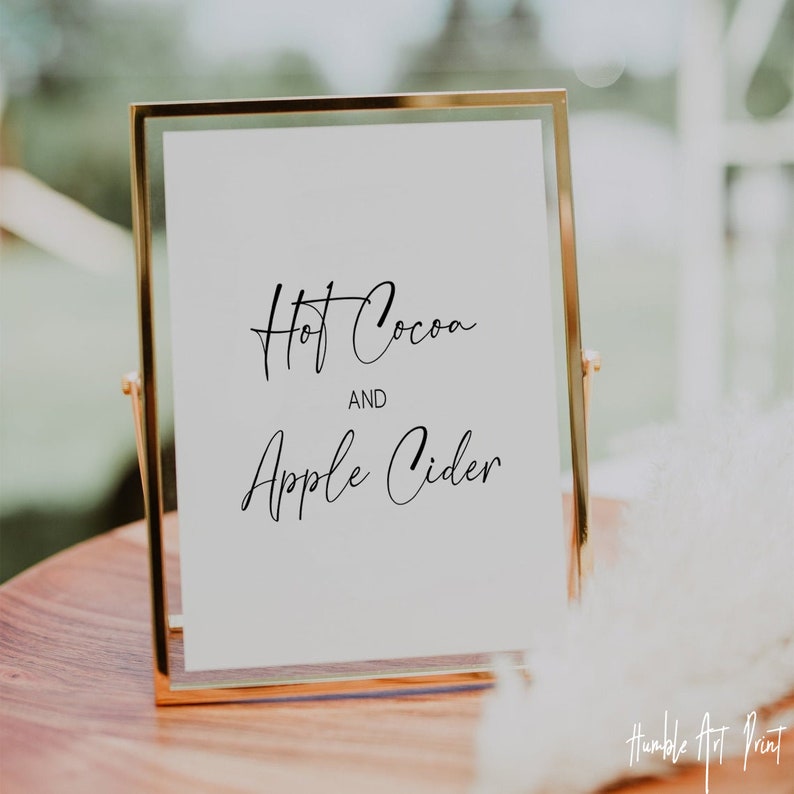 May include: A gold-framed sign with white background and black text that reads "Hot Cocoa and Apple Cider".