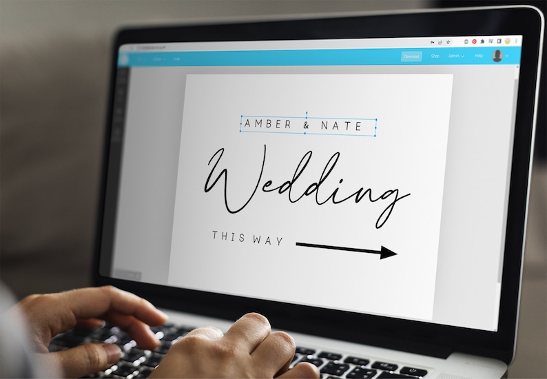 May include: A computer screen displaying a wedding sign with the text "Amber & Nate Wedding This Way" and an arrow pointing to the right.