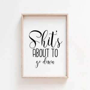 Puede incluir: Una impresi&oacute;n enmarcada con el texto "Shit's about to go down" en fuente cursiva negra sobre un fondo blanco.