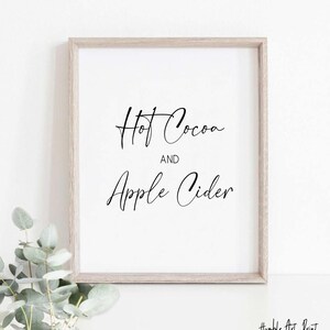 May include: A framed print with the text "Hot Cocoa and Apple Cider" in black cursive script on a white background.