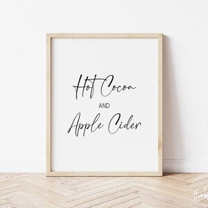 May include: A framed print with the text "Hot Cocoa and Apple Cider" in black cursive script on a white background.