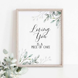 May include: A framed print with a white background and green watercolor leaves. The text reads "Loving You is a Piece of Cake."