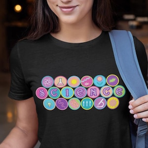 May include: Black t-shirt with the word "SCIENCE" spelled out in colorful, circular designs. The shirt is worn by a person holding a smartphone and wearing a blue backpack.