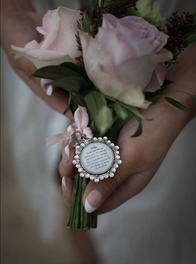 K&ouml;nnte beinhalten: Ein Strau&szlig; rosa Rosen mit gr&uuml;nen Bl&auml;ttern und einem silbernen Anh&auml;nger. Der Anh&auml;nger hat ein Blumenmuster und eine Botschaft, die lautet: "Heute bist du unser Blumenm&auml;dchen. Aber eines Tages wirst du den Strau&szlig; halten. Hier ist etwas Altes, das du an deinem Hochzeitstag tragen kannst. Liebe Katie & Shane 18.10.2019"
