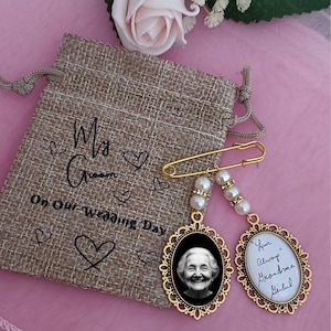 May include: A gold-coloured wedding day pin with two oval pendants, one with a photo and the other with handwritten text. The pin is attached to a hessian bag with the text "Ms. Green On Our Wedding Day."