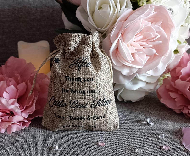 K&ouml;nnte beinhalten: Ein kleiner Jutesack mit Kordelzug. Der Sack ist personalisiert mit dem Namen "Alfie" und dem Text "Vielen Dank, dass du unser kleiner Trauzeuge bist. Liebe, Papa und Carol".