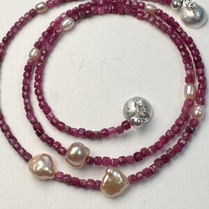 Op de afbeelding: Een meerstrengige ketting gemaakt van roze vierkante kralen en roze parel accenten. De ketting heeft twee zilveren sluitingen.