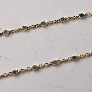 May include: A gold chain necklace with square-shaped links. The links are alternating gold and silver.