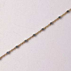 May include: A gold chain necklace with small square-shaped links.