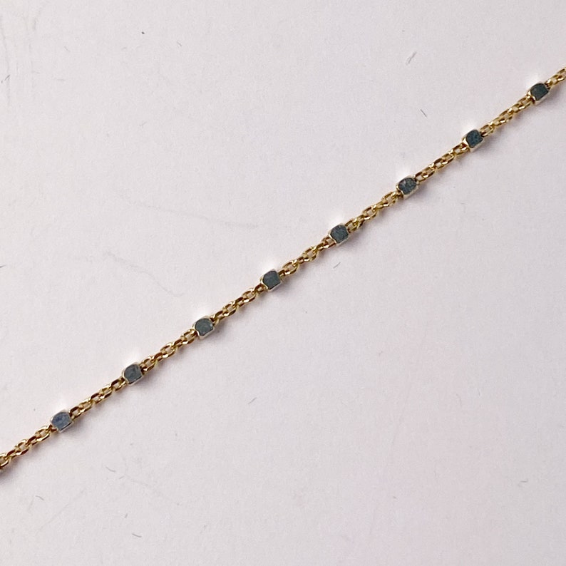 May include: A gold chain necklace with small square-shaped links.