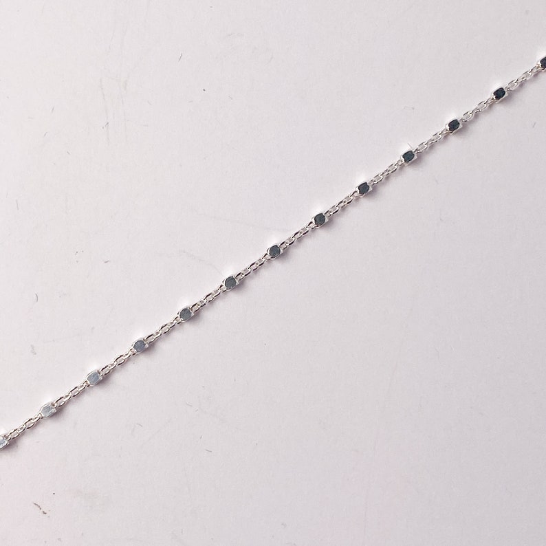 May include: A silver chain necklace with small, round links.