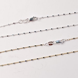 May include: Three silver chains with square links. The top two chains are silver and the bottom chain is gold.