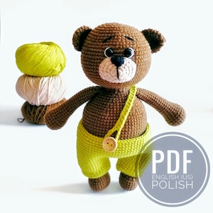 May include: Crochet pattern PDF for a brown teddy bear wearing yellow overalls with a wooden button. The pattern is available in English (US) and Polish.