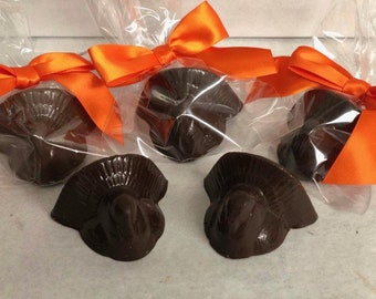 May include: Four chocolate turkey head favors wrapped in clear cellophane bags with orange ribbon bows.