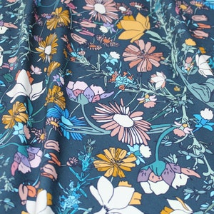 May include: Teal fabric with a floral print featuring pink, white, yellow, and blue flowers. The fabric has a subtle sheen and a soft texture.