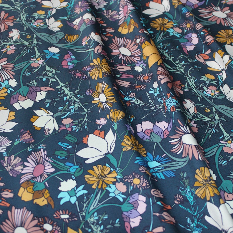 May include: A dark blue fabric with a floral pattern. The fabric features a variety of flowers in shades of pink, yellow, white, and blue.