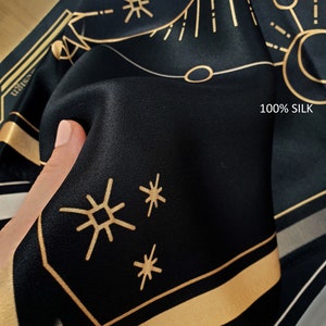 May include: Black silk fabric with a gold geometric pattern and the text "100% SILK".