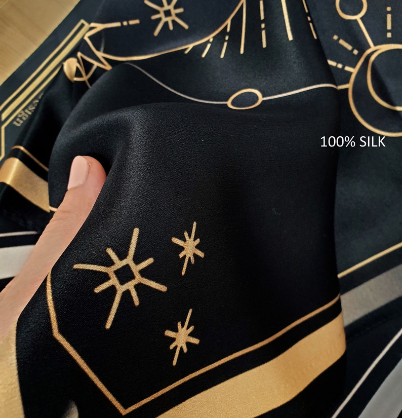 May include: Black silk fabric with a gold geometric pattern and the text "100% SILK".