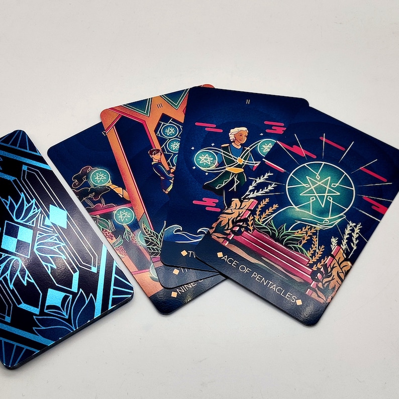 May include: A set of tarot cards with colorful illustrations and gold accents. The cards feature a blue background with a star design and the text "Ace of Pentacles".
