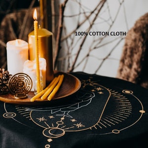 May include: Black cotton tablecloth with a gold geometric design featuring a circle, stars, and lines. The tablecloth is on a table with candles and a wooden tray.