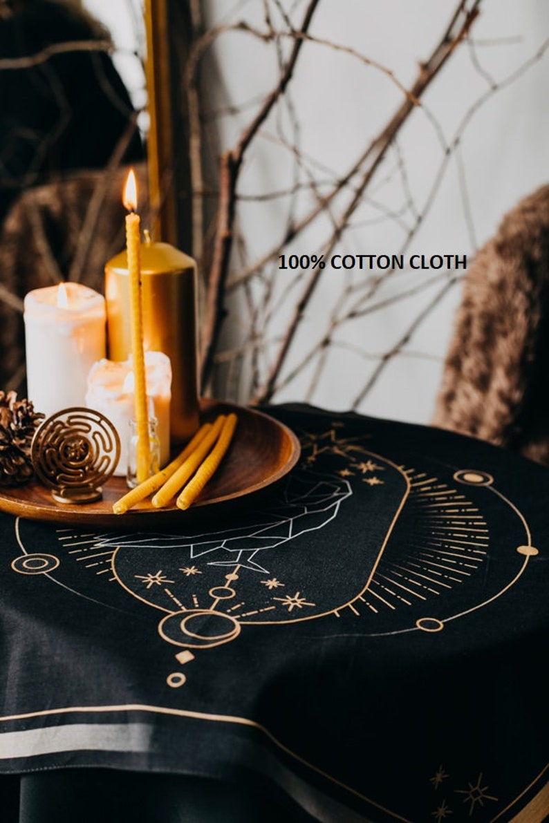 May include: Black cotton tablecloth with a gold geometric design featuring a circle, stars, and lines. The tablecloth is on a table with candles and a wooden tray.