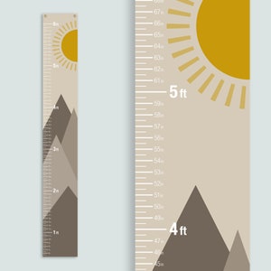 May include: A beige and brown growth chart with a mountain and sun design. The chart measures from 45 inches to 68 inches. The chart includes markings for feet and inches.