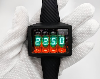 May include: A black wristwatch with a square face and four orange and green Nixie tubes displaying the time "22:50".