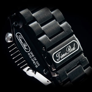 May include: Close-up of a black wristwatch with a metal band. The watch face and band feature the text "Time Red" in white script. The watch is marked "ONE OF XXX" and "R1.5.0IP67@".