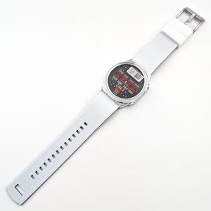 May include: A white wristwatch with a silver band and a digital display. The watch face has a black background with red and white numbers.