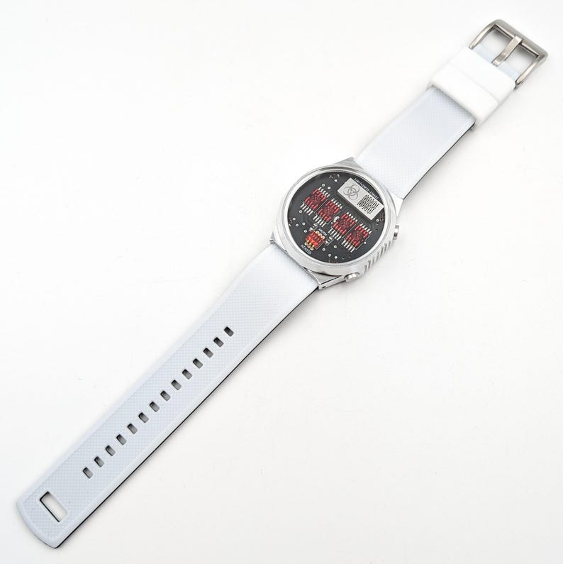 May include: A white wristwatch with a silver band and a digital display. The watch face has a black background with red and white numbers.