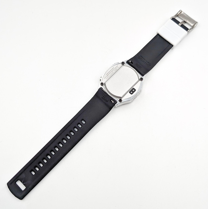 May include: A silver-toned wristwatch with a black rubber band. The watch face is round and has a black background. The watch has a silver-toned bezel with a black rubber band.