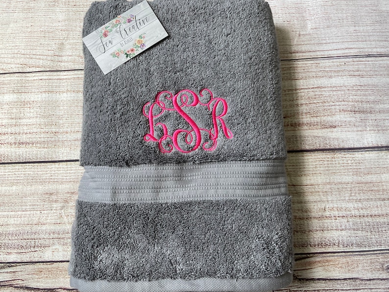 Puede incluir: Toalla de ba&ntilde;o gris con un monograma bordado en rosa "LSR".