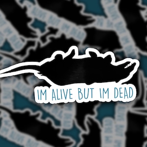 May include: Black and white silhouette of a rat with the text "IM ALIVE BUT IM DEAD" printed below.